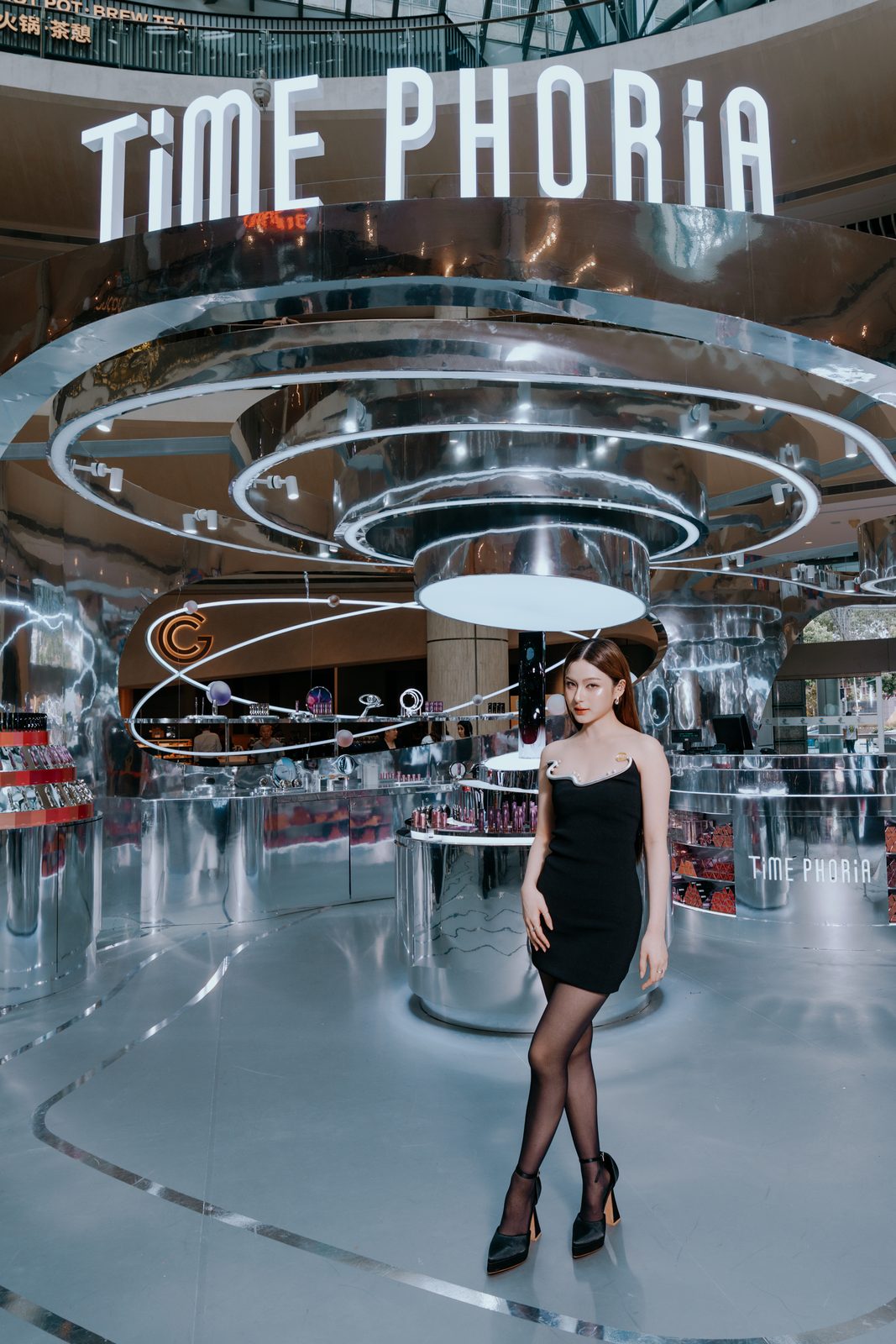Model standing inside a mirrored chrome installation under a Time Phoria sign