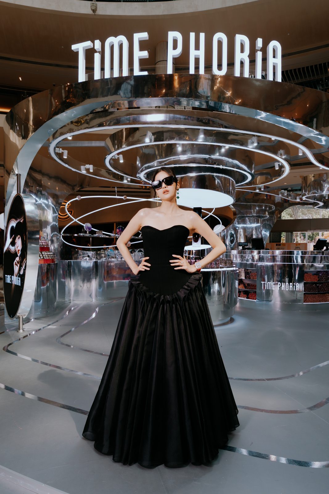 Model in a black ball gown in front of the Time Phoria installation