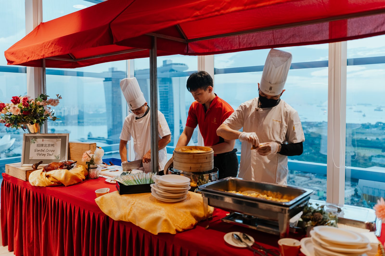 Chefs serving at a buffet station by a window overlooking the city