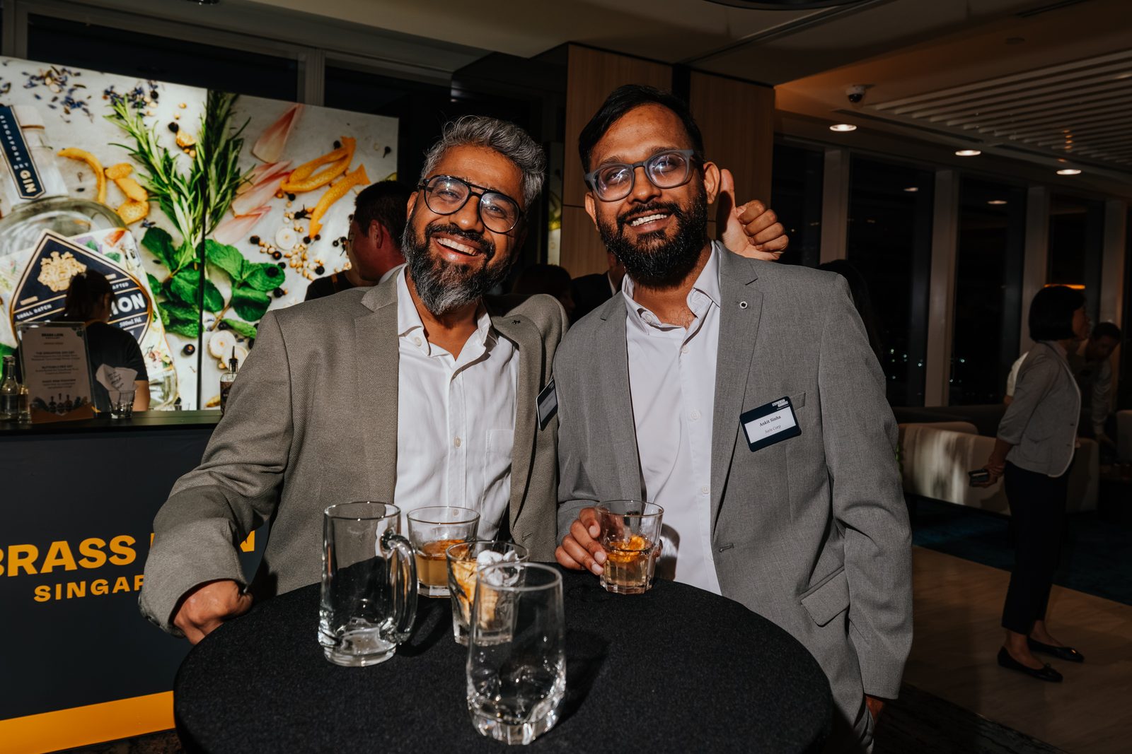 Two guests in suits smiling with drinks at a corporate evening