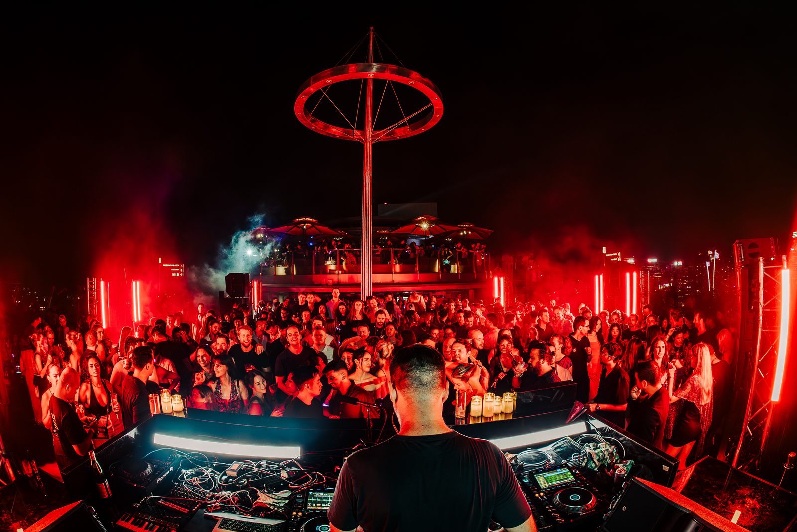 Crowd under red light at a rooftop event