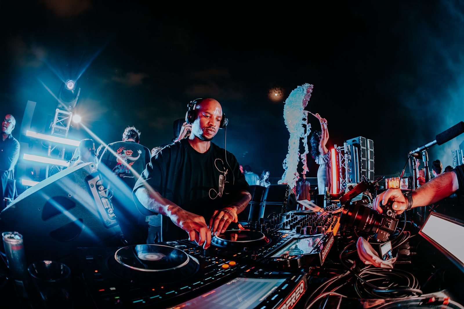 DJ under blue light with the skyline behind