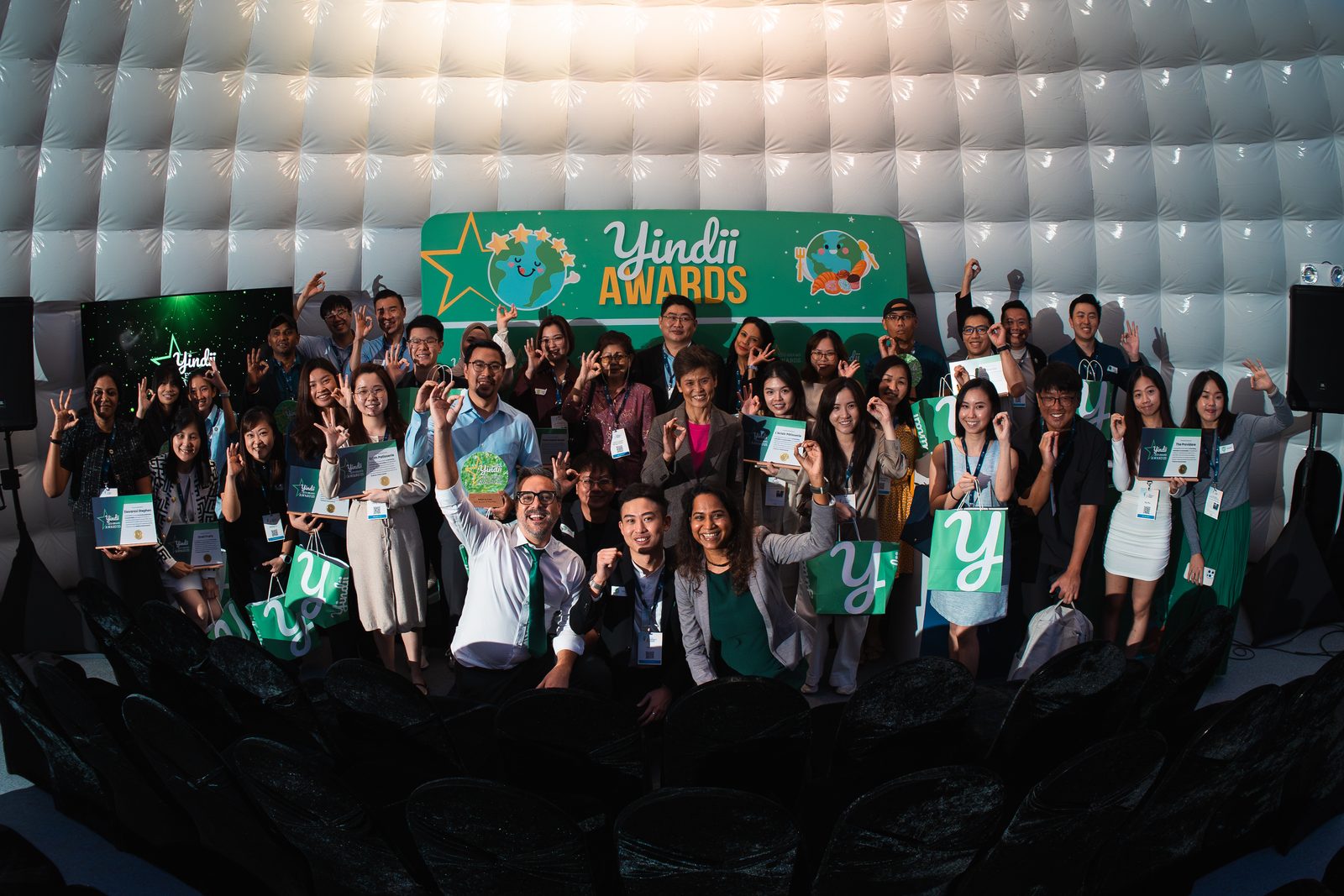 Award winners gathered on stage with their certificates, hands raised